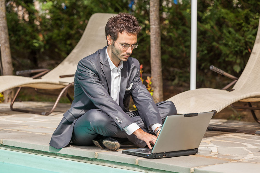 Man on laptop by the pool