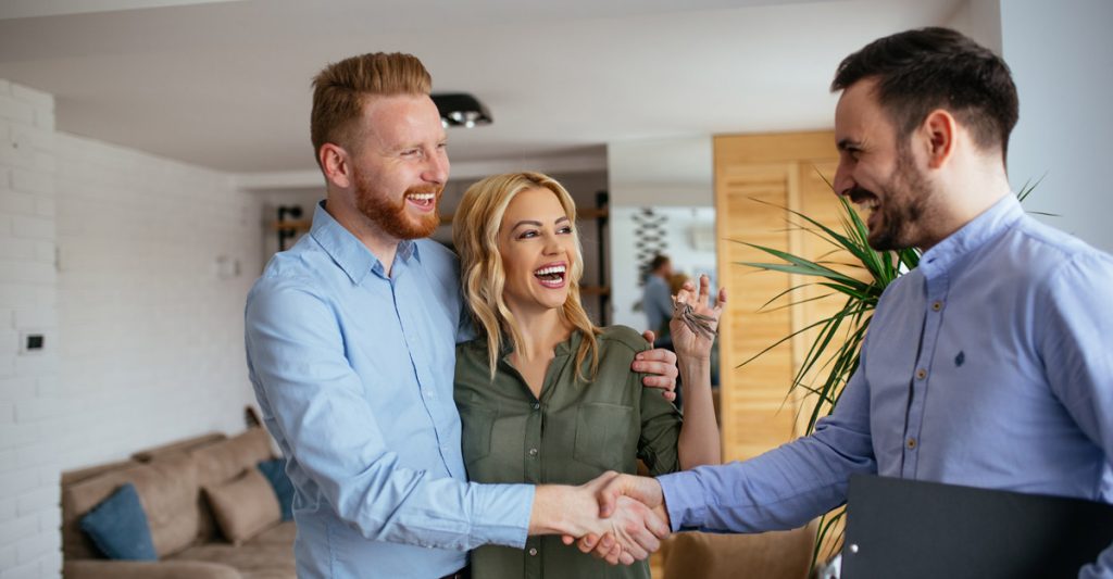 Couple shaking hands with business man